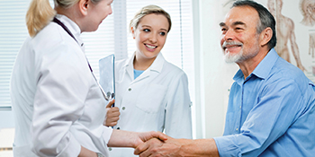 Zwei Mediziner, die einen Patienten begr&uuml;&szlig;en