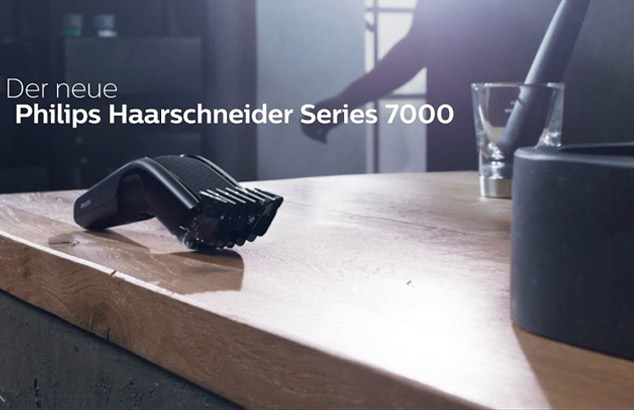 Der Philips Haarschneider der Serie 9000 liegt auf einem hellen Holztisch in einem hellen Raum.